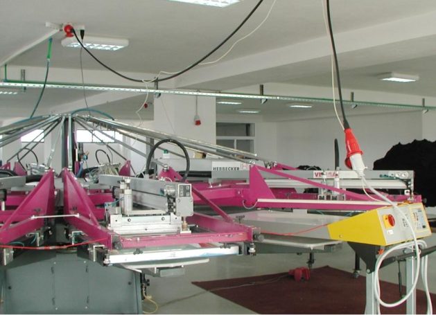 Druckmaschine in einer hellen Produktionshalle mit pinken Elementen.